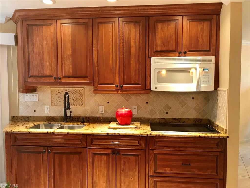 4256 31st Place Southwest Naples, FL 34116 - Photo 5 of 20 a kitchen with granite countertop wooden cabinets and a sink