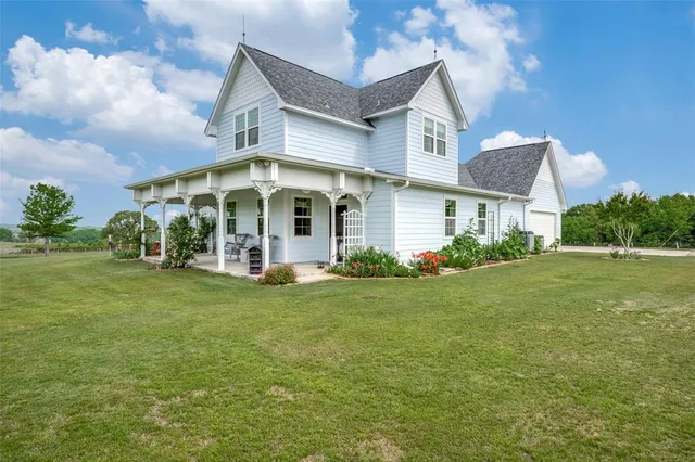 a view of a white house next to a yard with big trees