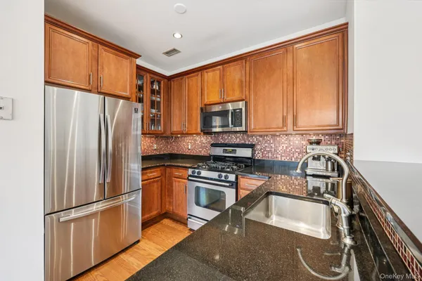 a kitchen with granite countertop a refrigerator stove and microwave