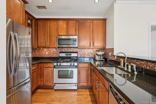 a kitchen with stainless steel appliances granite countertop a stove a sink and a refrigerator