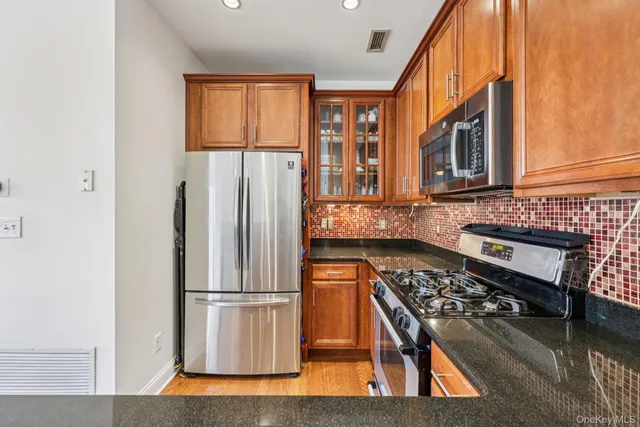 a kitchen with stainless steel appliances granite countertop a refrigerator a stove and a sink