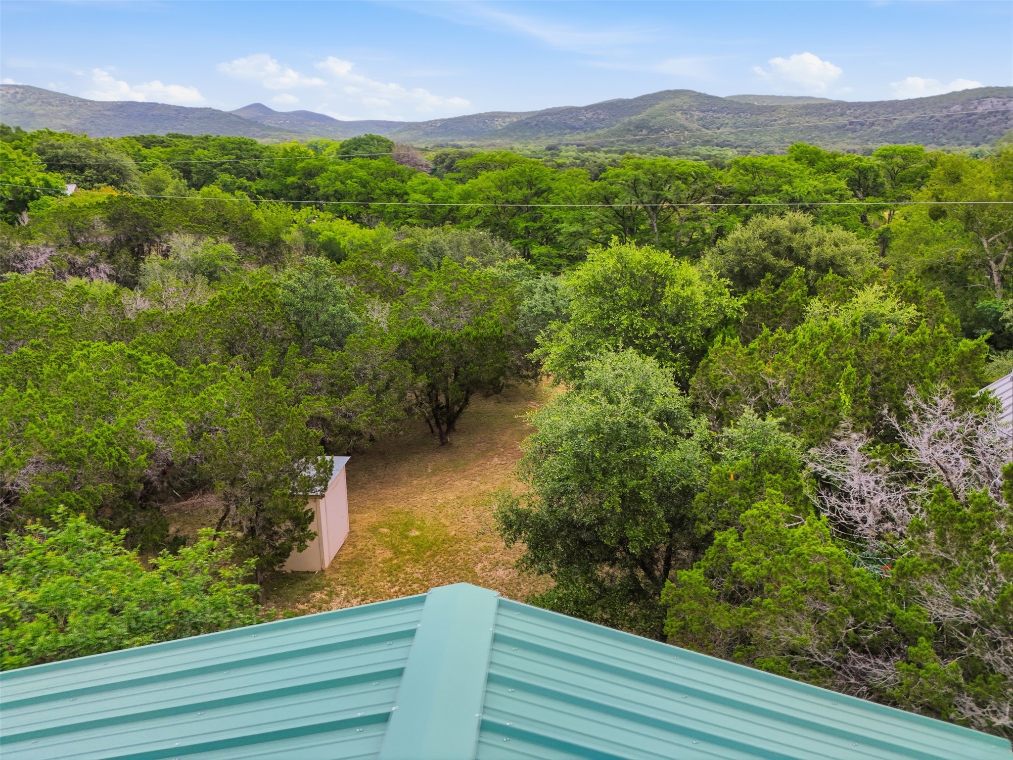 1260 Magers Road Concan, TX 78838 - Photo 33 of 40 A verdant landscape unfolds, showcasing a natural setting with distant hills under a clear sky.