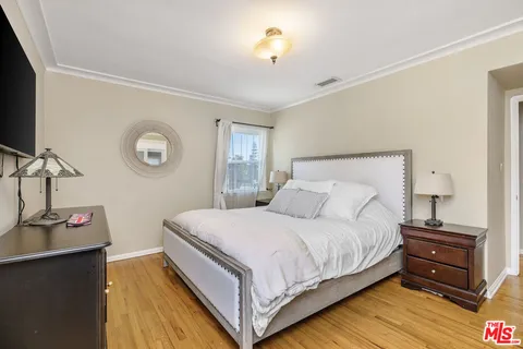a bedroom with a bed and a flat tv screen on the dresser