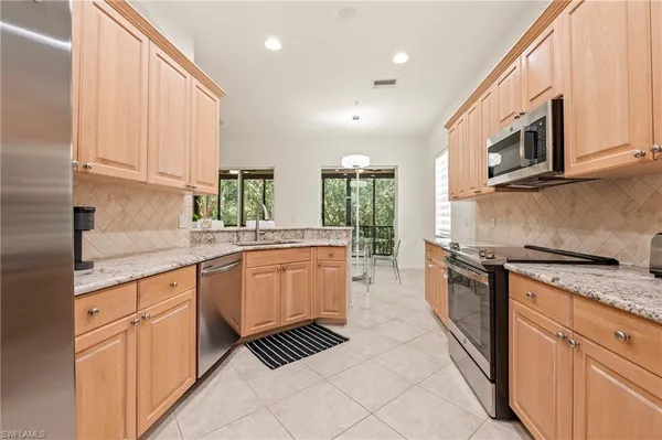 a large kitchen with stainless steel appliances granite countertop a stove a sink and a microwave