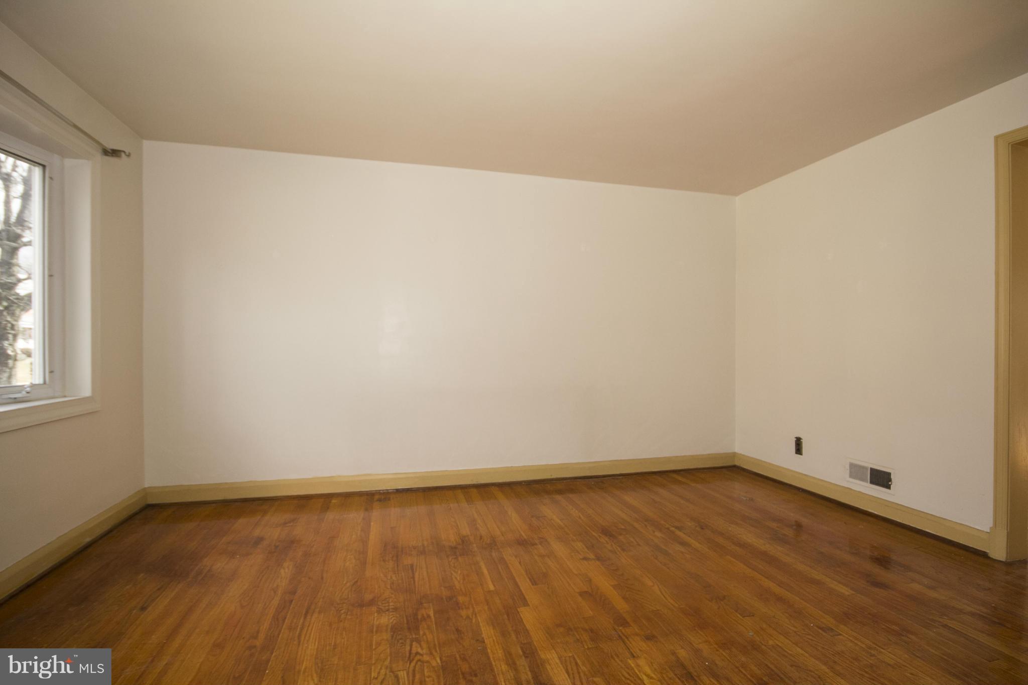 1673 Northbourne Road Baltimore, MD 21239 - Photo 2 of 21 a view of an empty room with wooden floor and a window