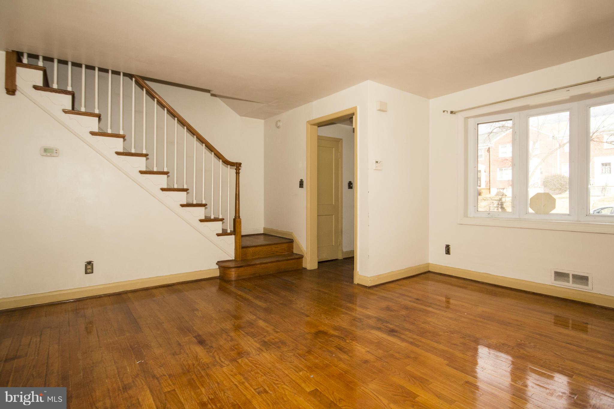 1673 Northbourne Road Baltimore, MD 21239 - Photo 4 of 21 a view of an empty room with wooden floor and stairs