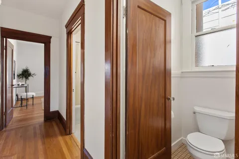 a bathroom with a toilet and a hardwood floor