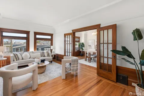 a living room with furniture large window and wooden floor
