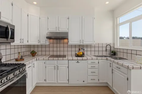 a kitchen with white cabinets and appliances