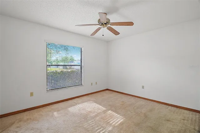 an empty room with ceiling fan and window
