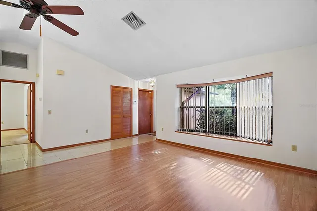 a view of an empty room with a window and wooden floor