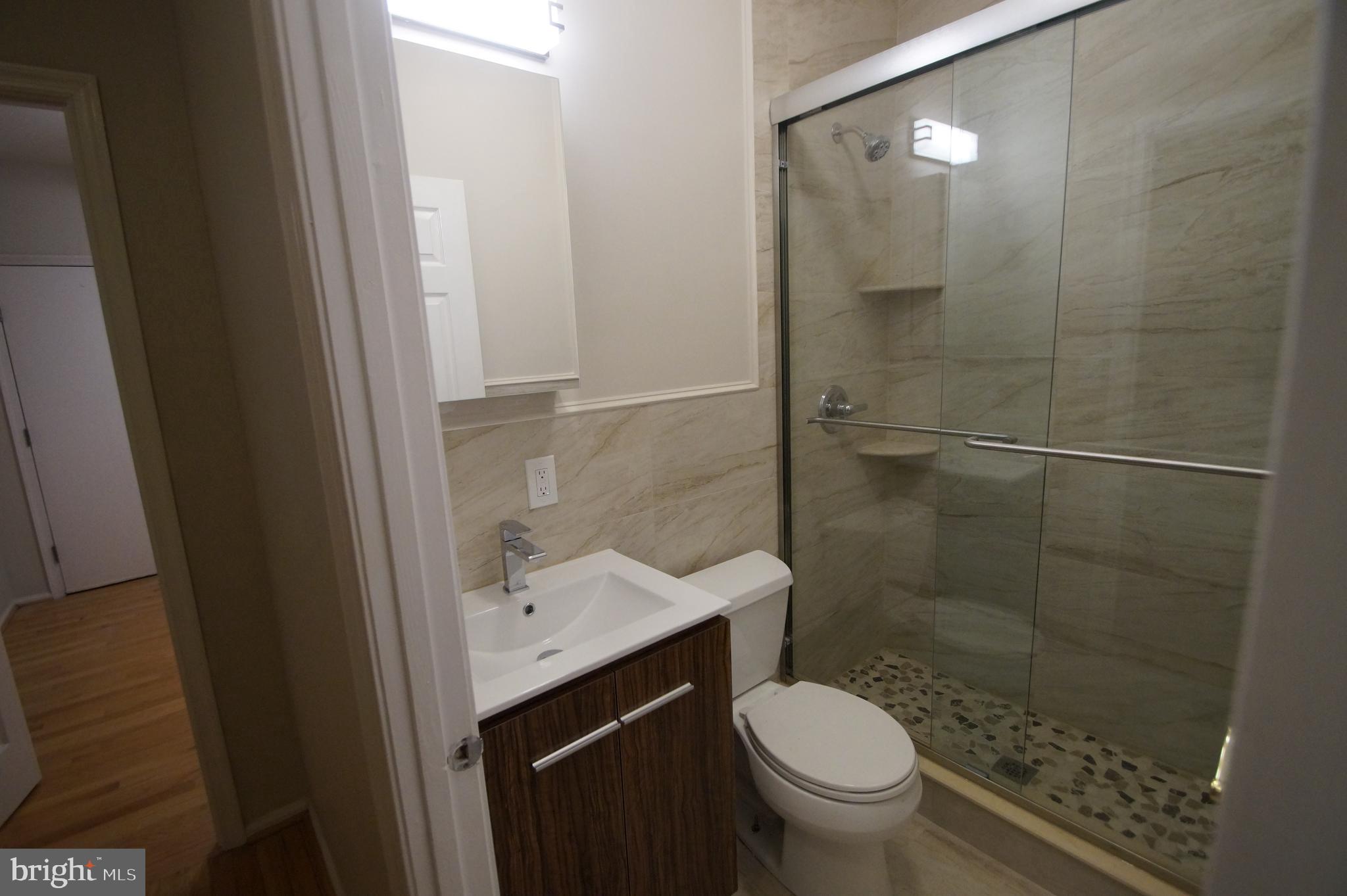 1004 Christian Street Philadelphia, PA 19147 - Photo 24 of 34 a bathroom with a granite countertop toilet a sink and a mirror