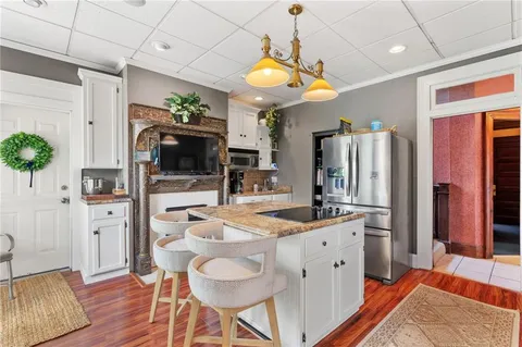a kitchen with stainless steel appliances kitchen island granite countertop a refrigerator a stove a microwave oven a dining table and chairs with wooden floor