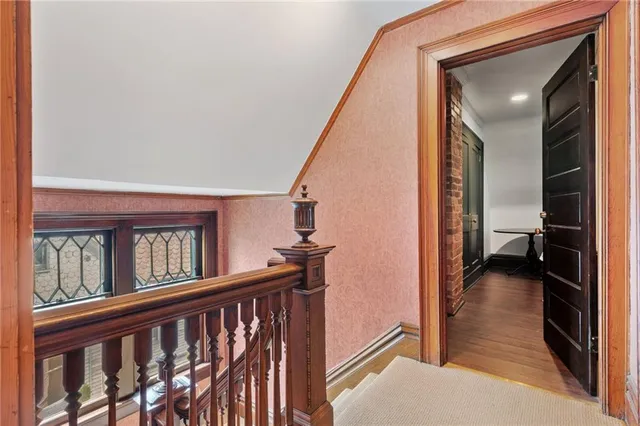 a view of a hallway to a livingroom with wooden floor and staircase