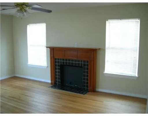 an empty room with wooden floor fireplace and windows
