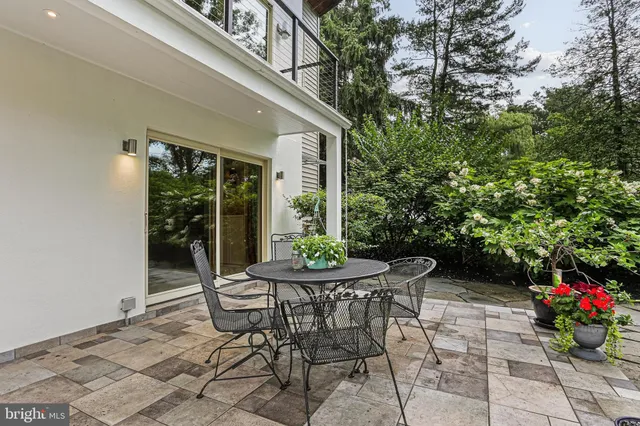 a view of a patio with table and chairs potted plants and floor to ceiling window