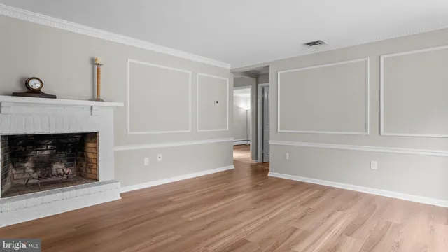 a view of an empty room with wooden floor fireplace and a window