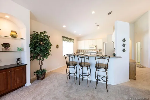 a kitchen with stainless steel appliances granite countertop a table chairs sink and cabinets