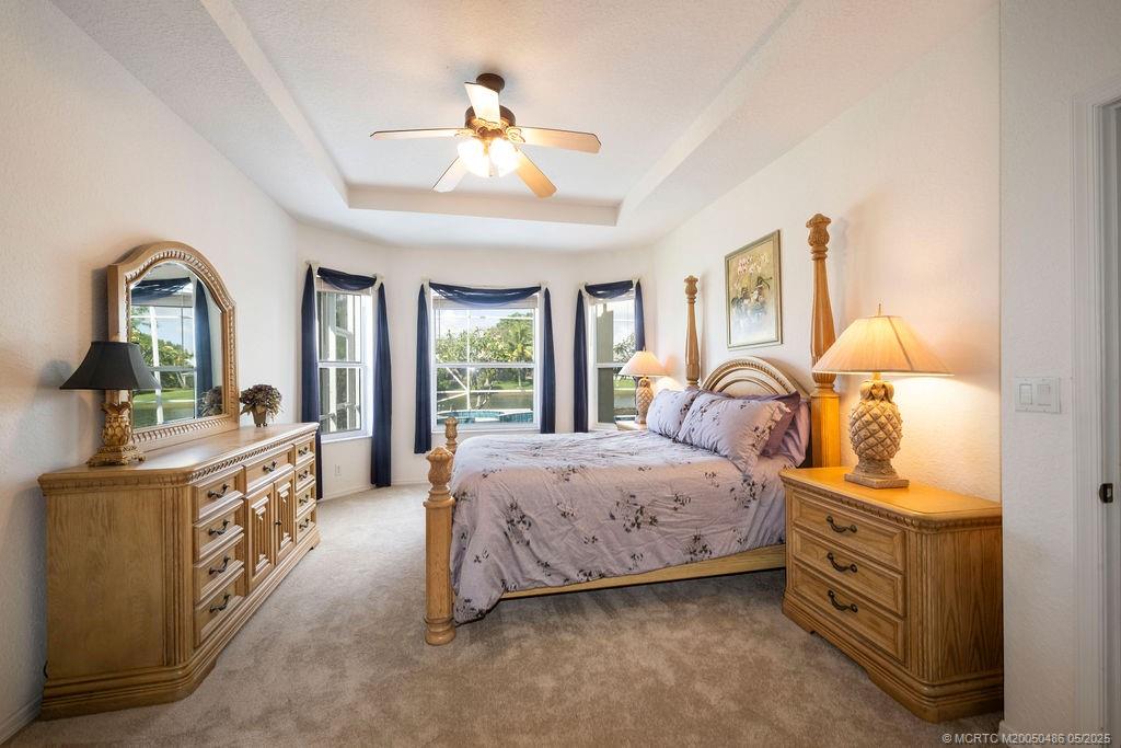 2096 Northwest Marsh Rabbit Lane Stuart, FL 34994 - Photo 42 of 58 a spacious bedroom with a bed and a chandelier