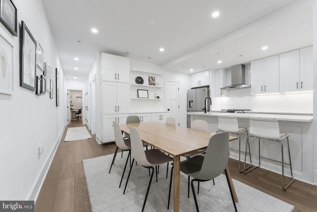 a kitchen with stainless steel appliances kitchen island granite countertop a dining table chairs refrigerator and sink