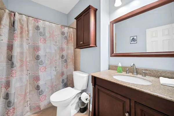 a bathroom with a granite countertop toilet sink and mirror