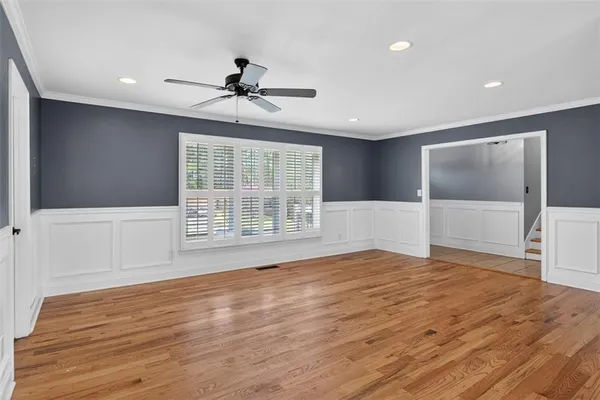 a view of an empty room with wooden floor and a window