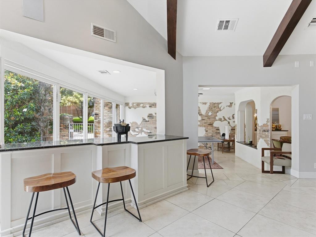 6160 Spring Valley Road Dallas, TX 75240 - Photo 20 of 40 Breakfast bar with a dark stone countertop and white paneled base
