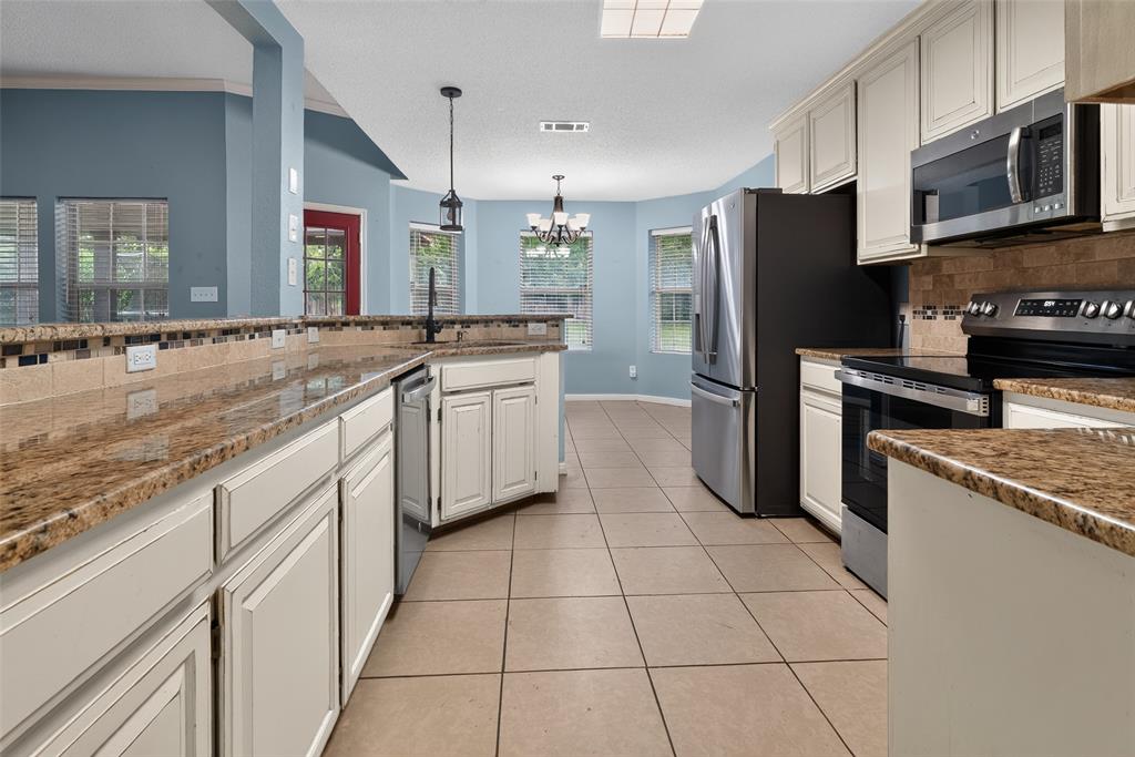 124 Topaz Circle Hewitt, TX 76643 - Photo 11 of 35 Kitchen featuring granite countertops, tile flooring, white cabinetry, stainless steel appliances, and a tiled backsplash