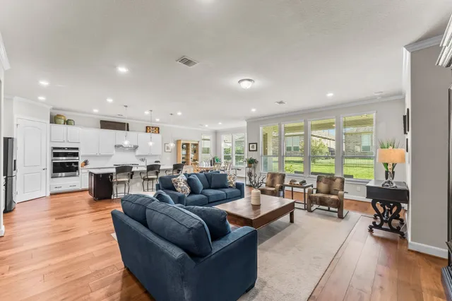 a living room with furniture floor to ceiling window and kitchen view