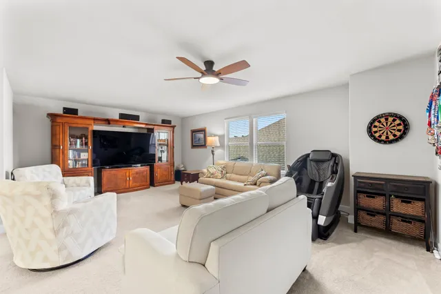 a living room with furniture a flat screen tv and ceiling fan