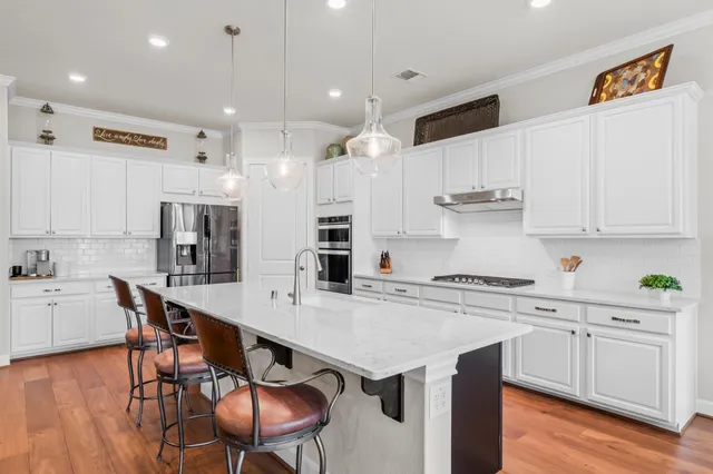 a kitchen with stainless steel appliances granite countertop a table chairs sink refrigerator and cabinets