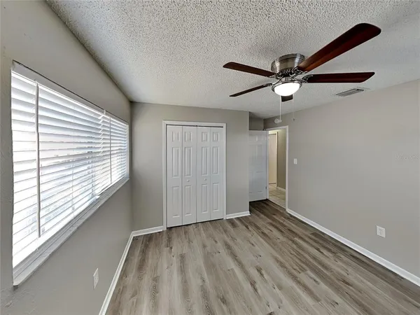 a view of empty room with wooden floor and fan