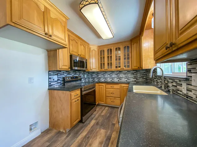 a kitchen with stainless steel appliances granite countertop a sink and wooden cabinets