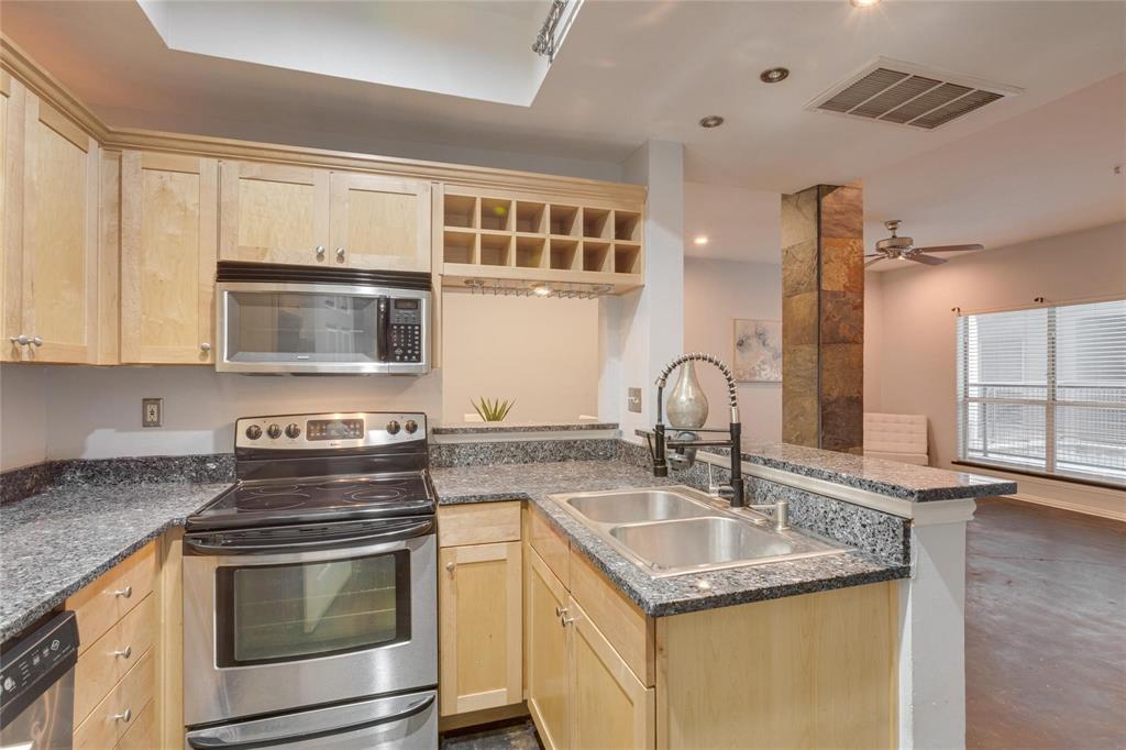4104 North Hall Street, Unit 102 Dallas, TX 75219 - Photo 12 of 18 Kitchen featuring stainless steel appliances, light wood-finish cabinetry, granite countertops, and a dual basin sink with a modern faucet