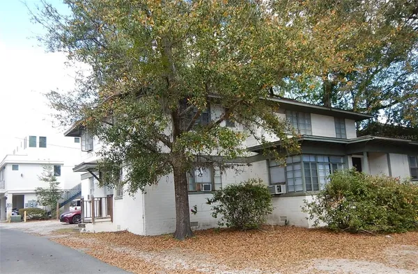 a view of a white house with a tree and plants