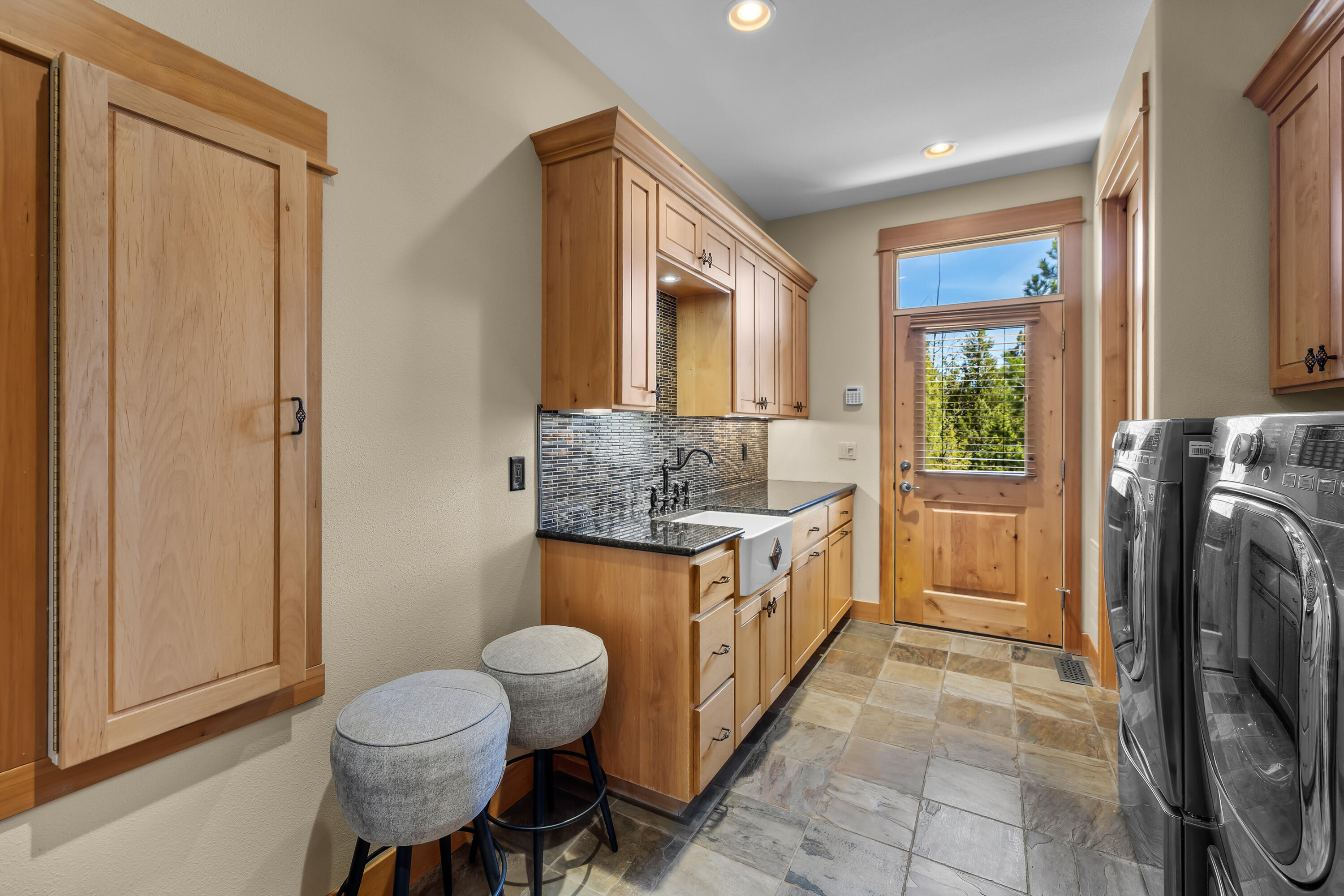 64145 Hunnell Road Bend, OR 97703 - Photo 36 of 65 A spacious laundry room adds everyday function with built-in cabinetry, utility sink, tile flooring and direct exterior access ? ideal for acreage living, pets, gear and easy transitions from the outdoors.