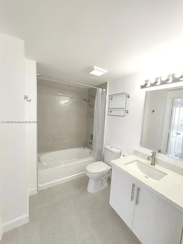 a bathroom with a bathtub shower sink vanity mirror and toilet