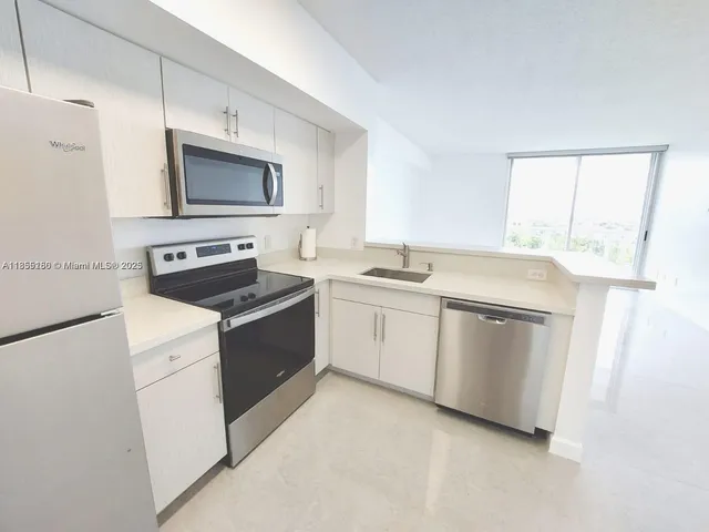 a kitchen with white cabinets appliances and sink