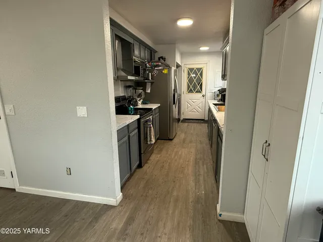 a view of a kitchen with refrigerator and wooden floor