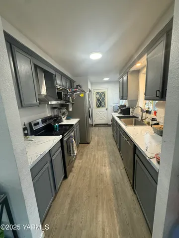 a kitchen with stainless steel appliances granite countertop a stove top oven a sink dishwasher a refrigerator and cabinets with wooden floor