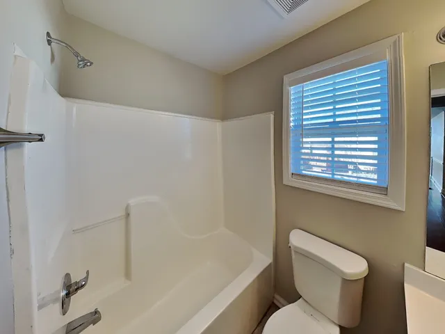 a white toilet sitting next to a bath tub