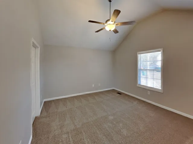 an empty room with chandelier fan and windows