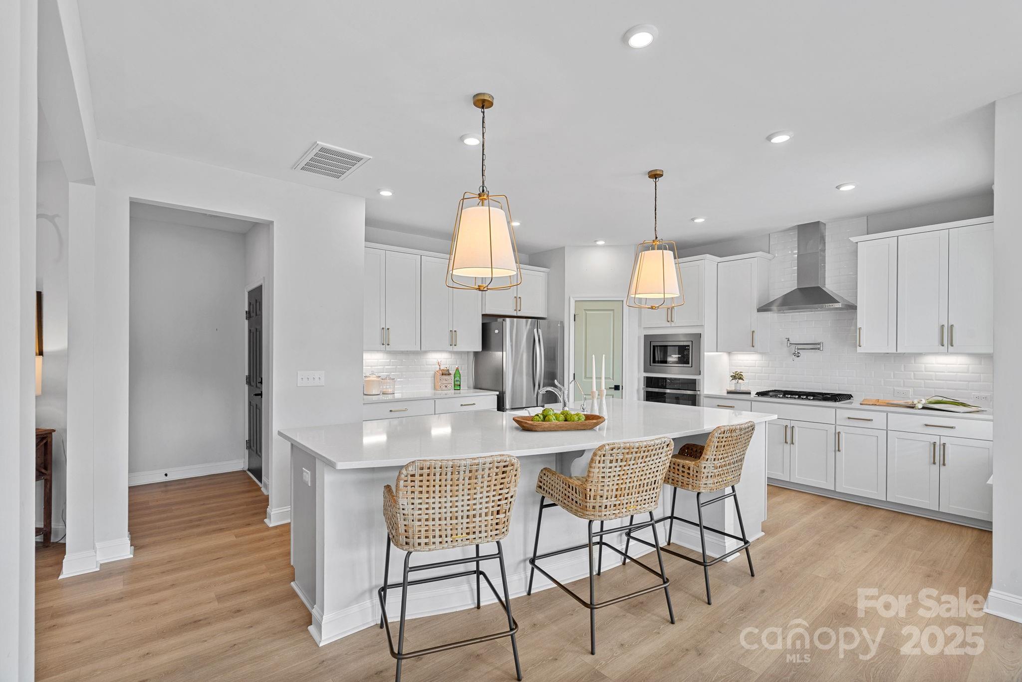 2253 Masons Bend Drive Fort Mill, SC 29708 - Photo 11 of 48 a kitchen with stainless steel appliances granite countertop a sink a stove a refrigerator and island with wooden floor