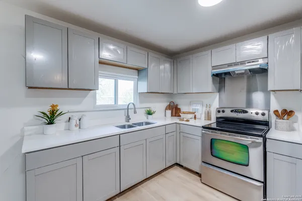 a kitchen with a sink a stove cabinets and stainless steel appliances