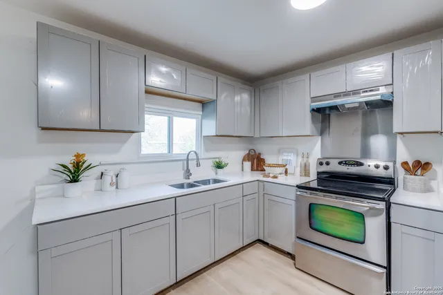 a kitchen with a sink a stove cabinets and stainless steel appliances