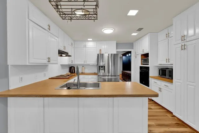 a kitchen with kitchen island a counter top space a sink stainless steel appliances and cabinets