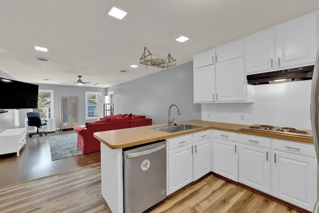 a kitchen with stainless steel appliances granite countertop a sink stove and white cabinets with wooden floor