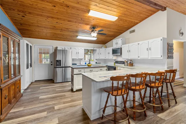 a kitchen with stainless steel appliances kitchen island granite countertop a dining table chairs and white cabinets