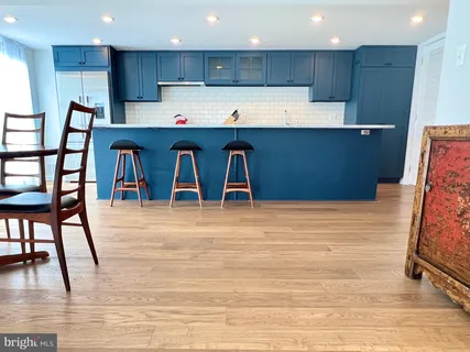 a kitchen with stainless steel appliances kitchen island granite countertop a table chairs sink and cabinets