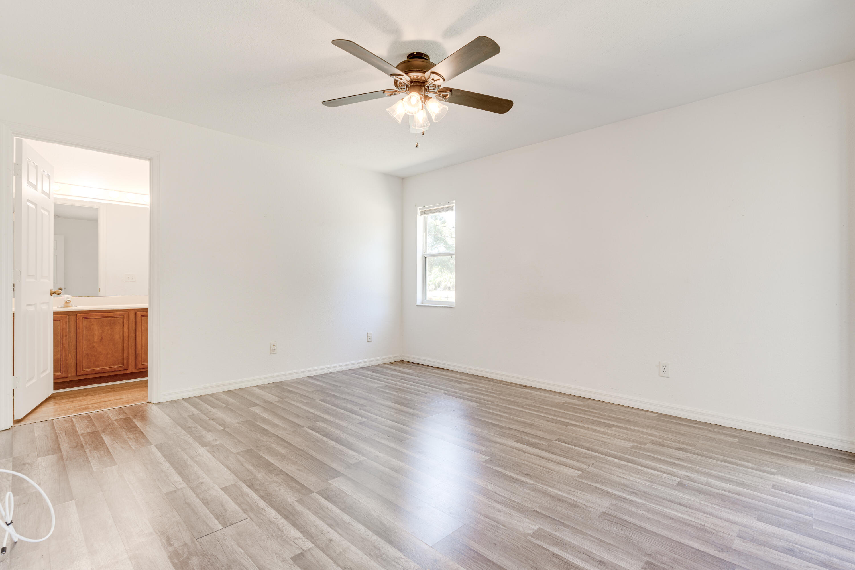 500 Topeka Road Southwest Palm Bay, FL 32908 - Photo 9 of 12 an empty room with wooden floor and a ceiling fan